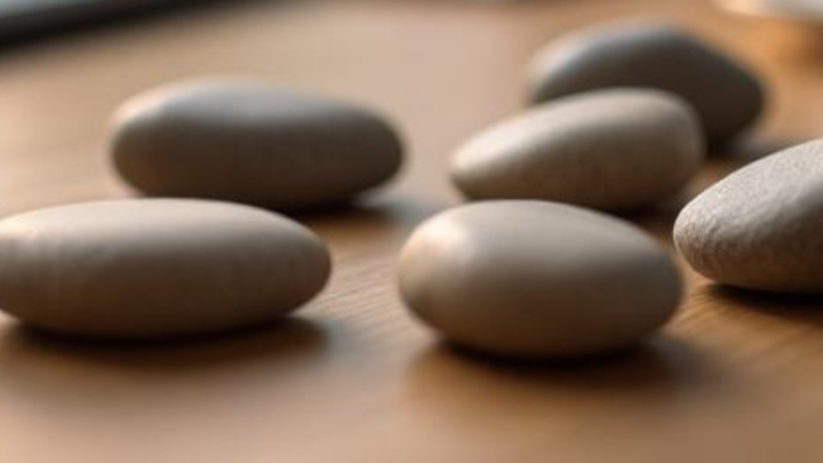 Smooth unmarked stones on a warm wooden tabletop, arranged like a calm 90-day publishing rhythm for a law firm.