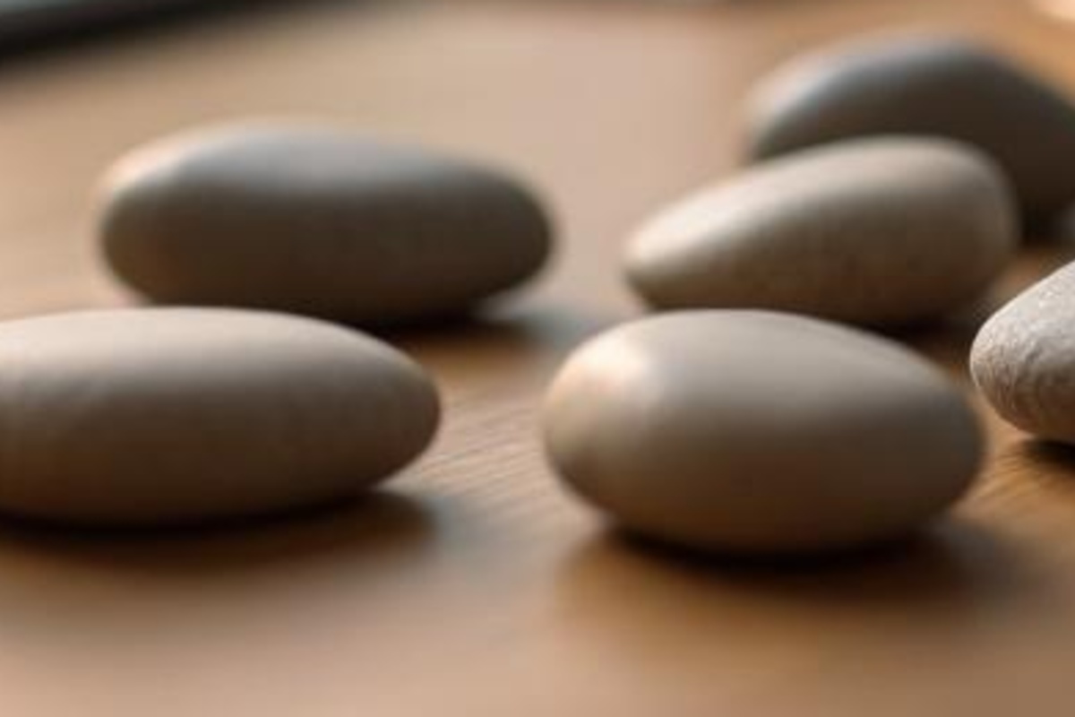 Smooth unmarked stones on a wooden tabletop, suggesting grouped content topics in a calm publishing plan.