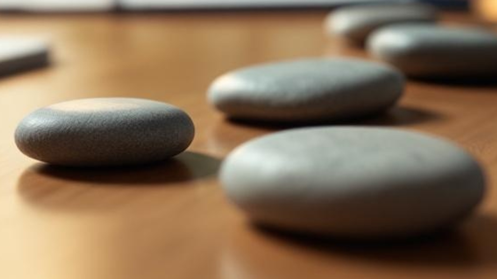 Smooth unmarked stones on a warm wooden tabletop, grouped into separate paths to symbolize client situation pages