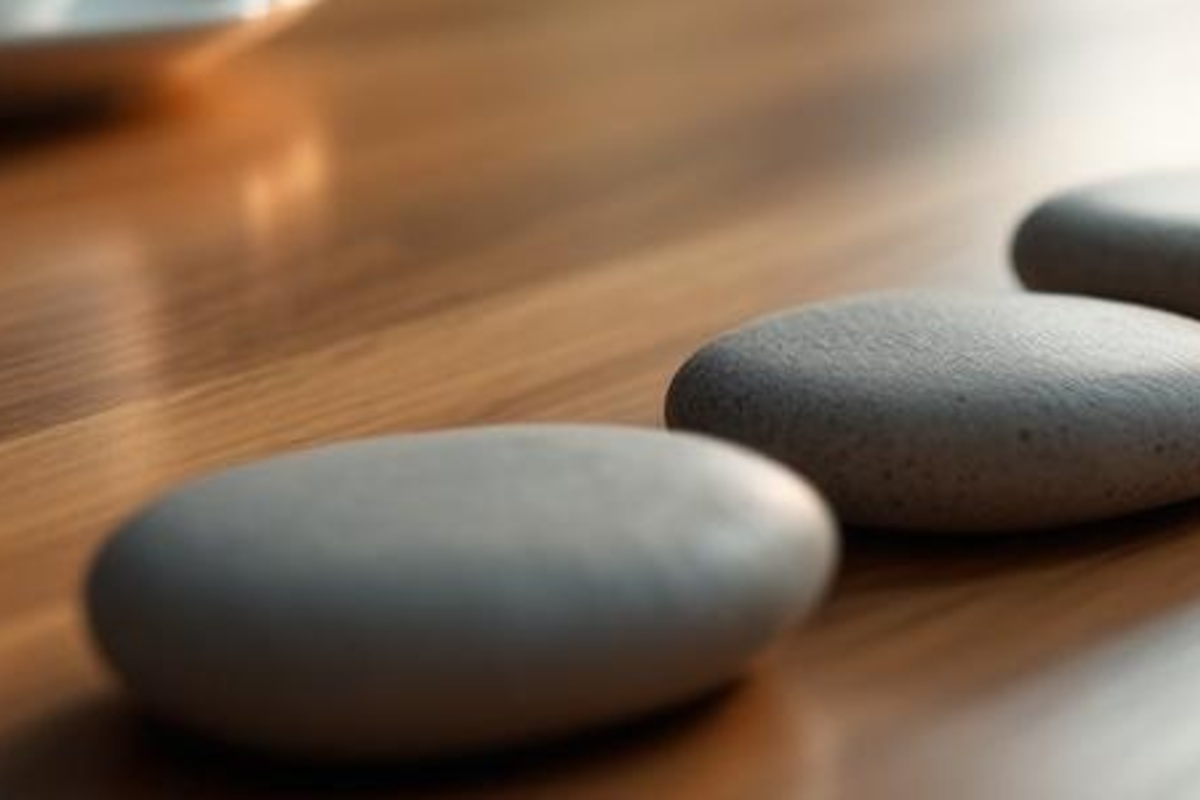 Close view of smooth unmarked stones forming a steady reminder path across a warm wooden tabletop