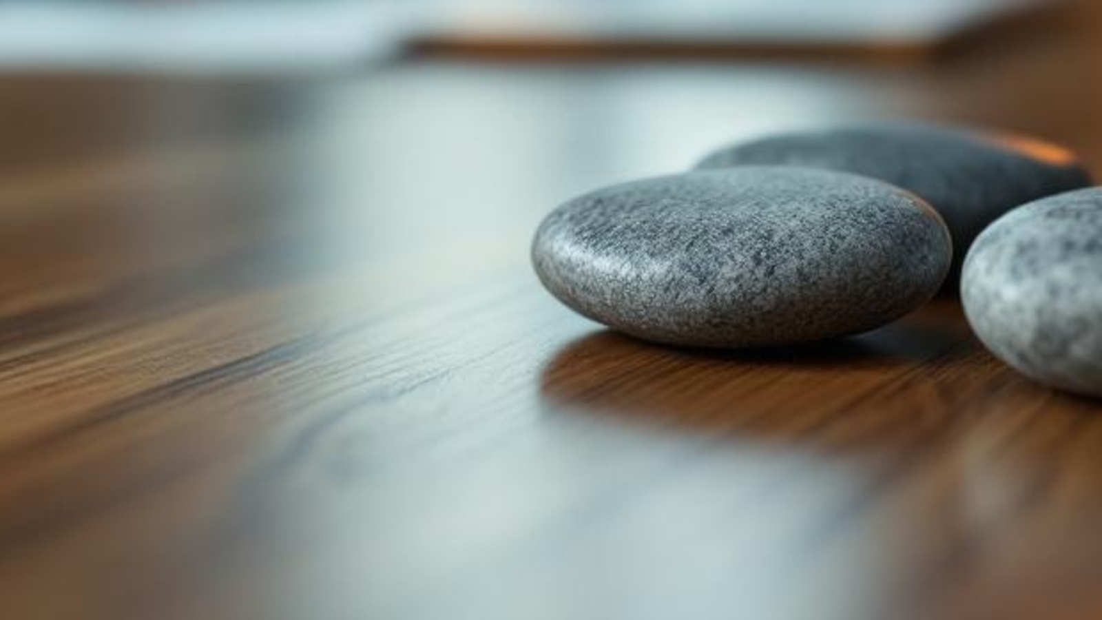 Smooth unmarked stones on a warm wooden tabletop, suggesting calm value clarity without papers, text, or screens.
