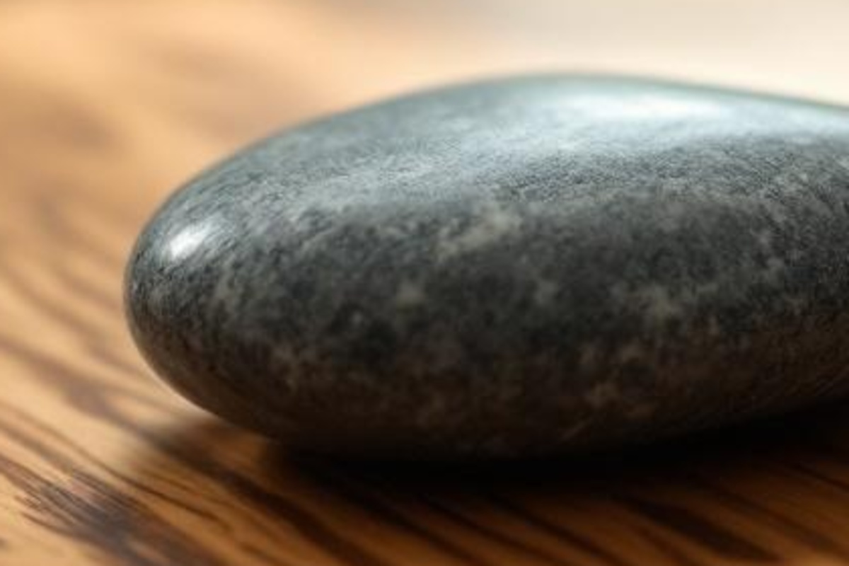 Smooth unmarked stones and warm wood grain on a clean tabletop, symbolizing calm fee and value clarity.