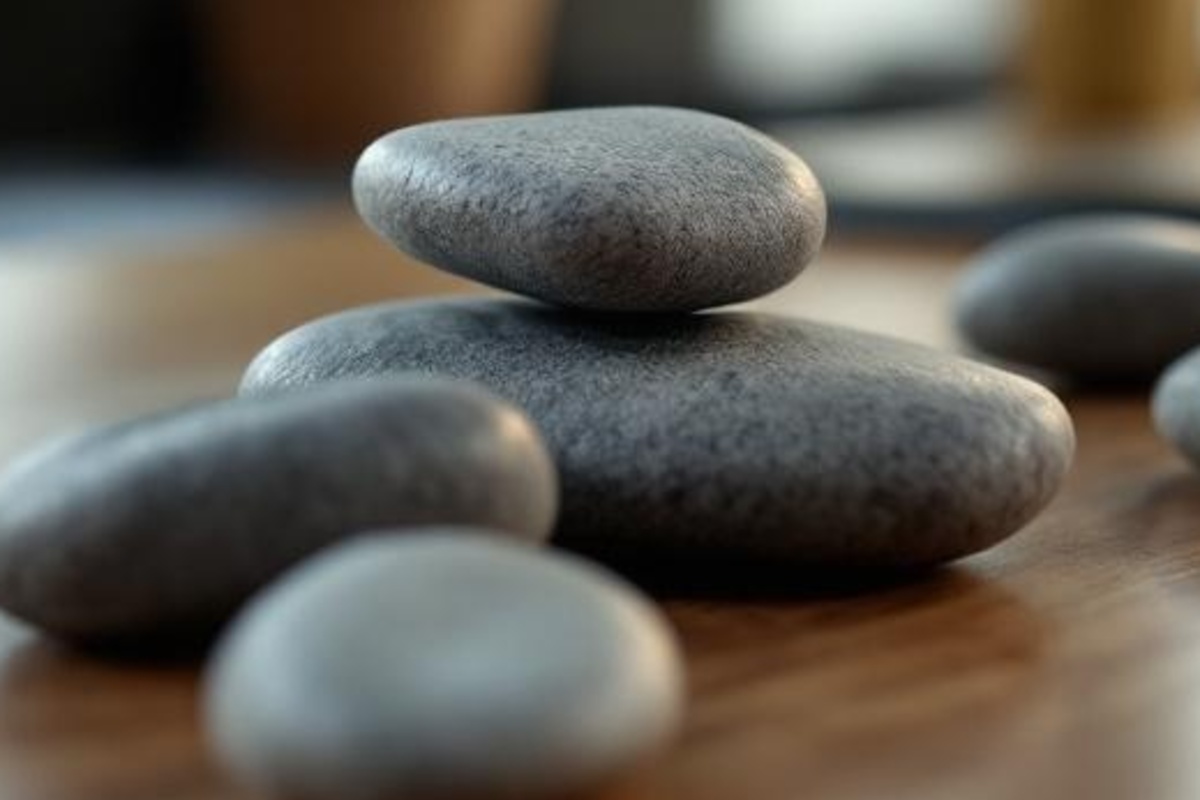 Close-up of smooth stones and a plant on a wooden table, symbolizing a simple registration path for a workshop