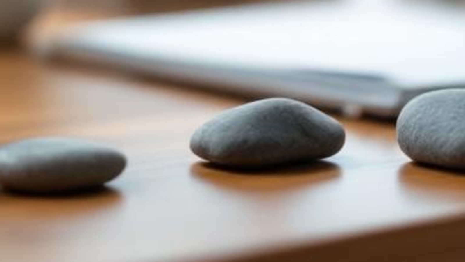 Close-up of smooth gray stones on a warm wooden tabletop, arranged as a calm metaphor for trust planning steps.