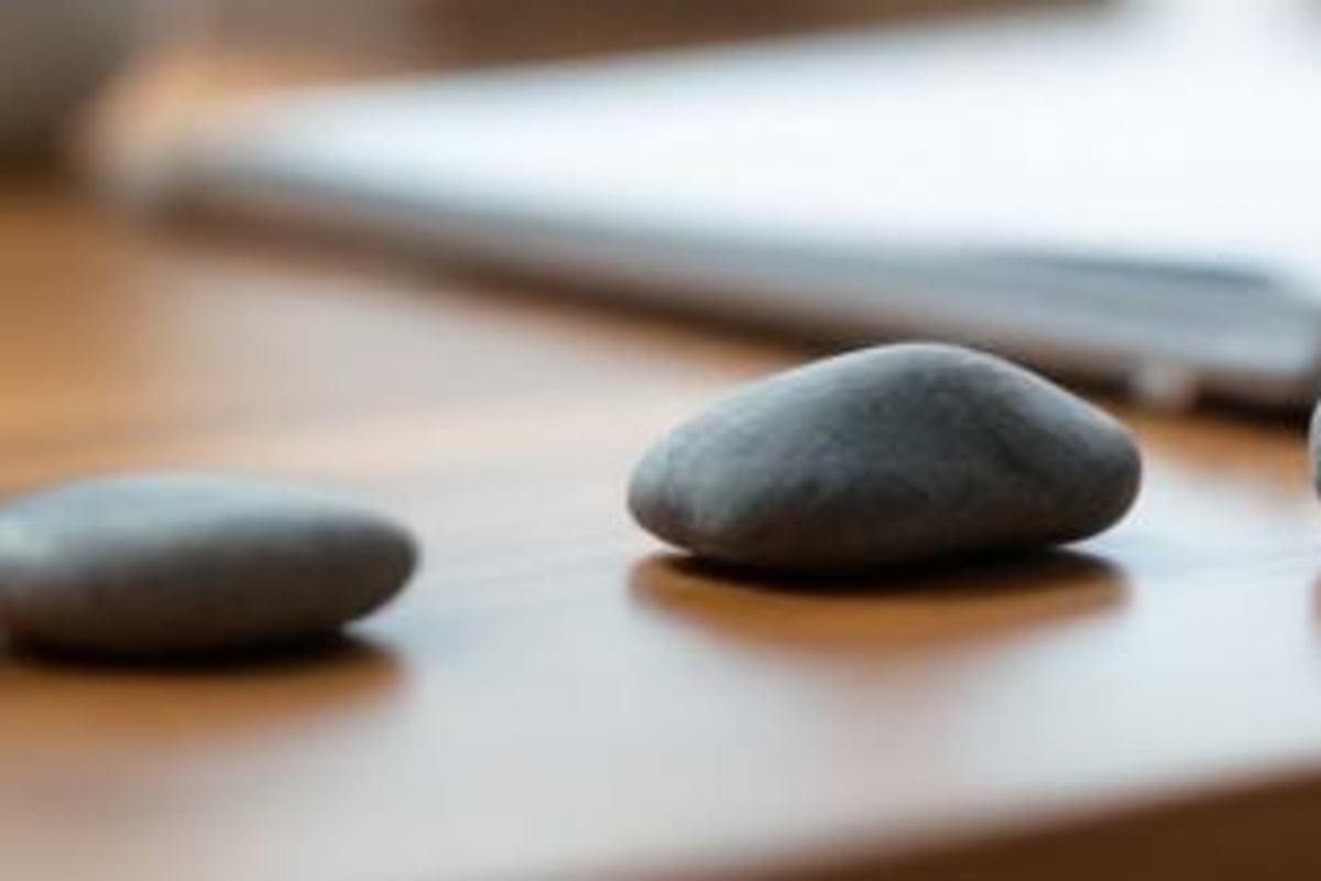 Close-up of smooth gray stones resting on a warm wooden tabletop with soft light and no paper or screens.