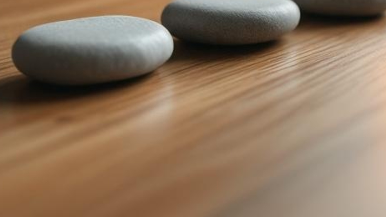 Smooth unmarked stones on a warm wooden tabletop, arranged as a calm metaphor for connecting trust documents to real assets.