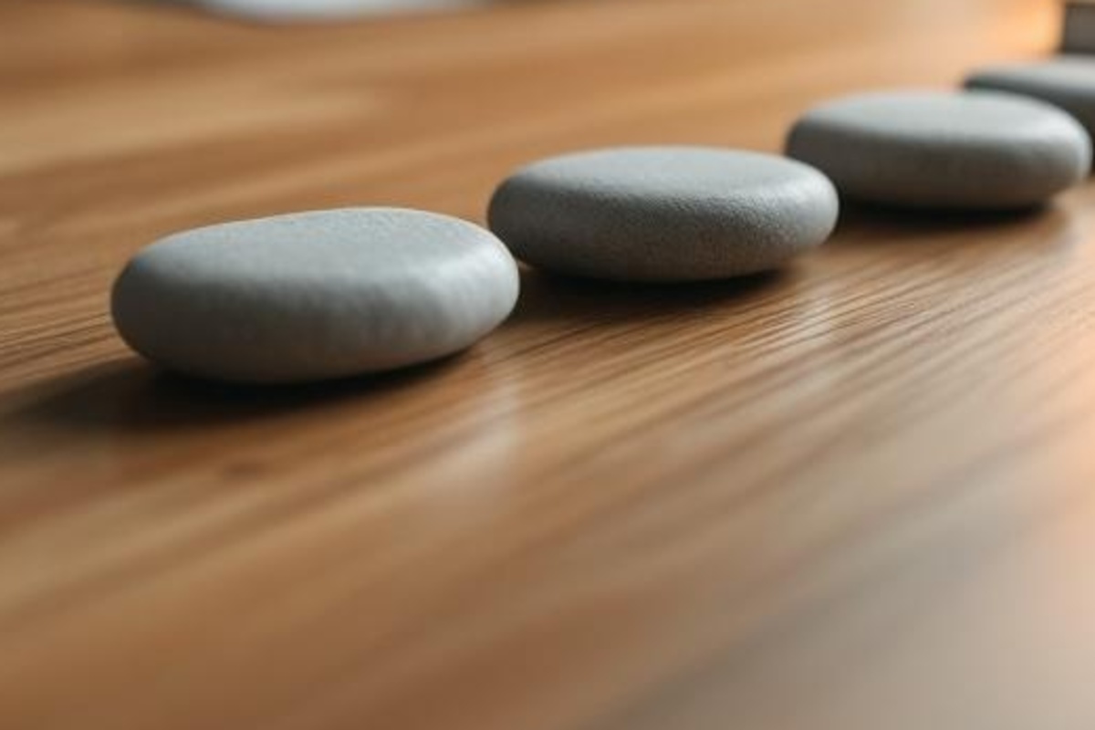 Smooth unmarked stones on a clean wooden tabletop, representing clear trust funding steps without paper or screens.